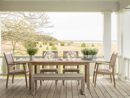 Teak table 和 chairs on a deck overlooking the ocean 和 marsh